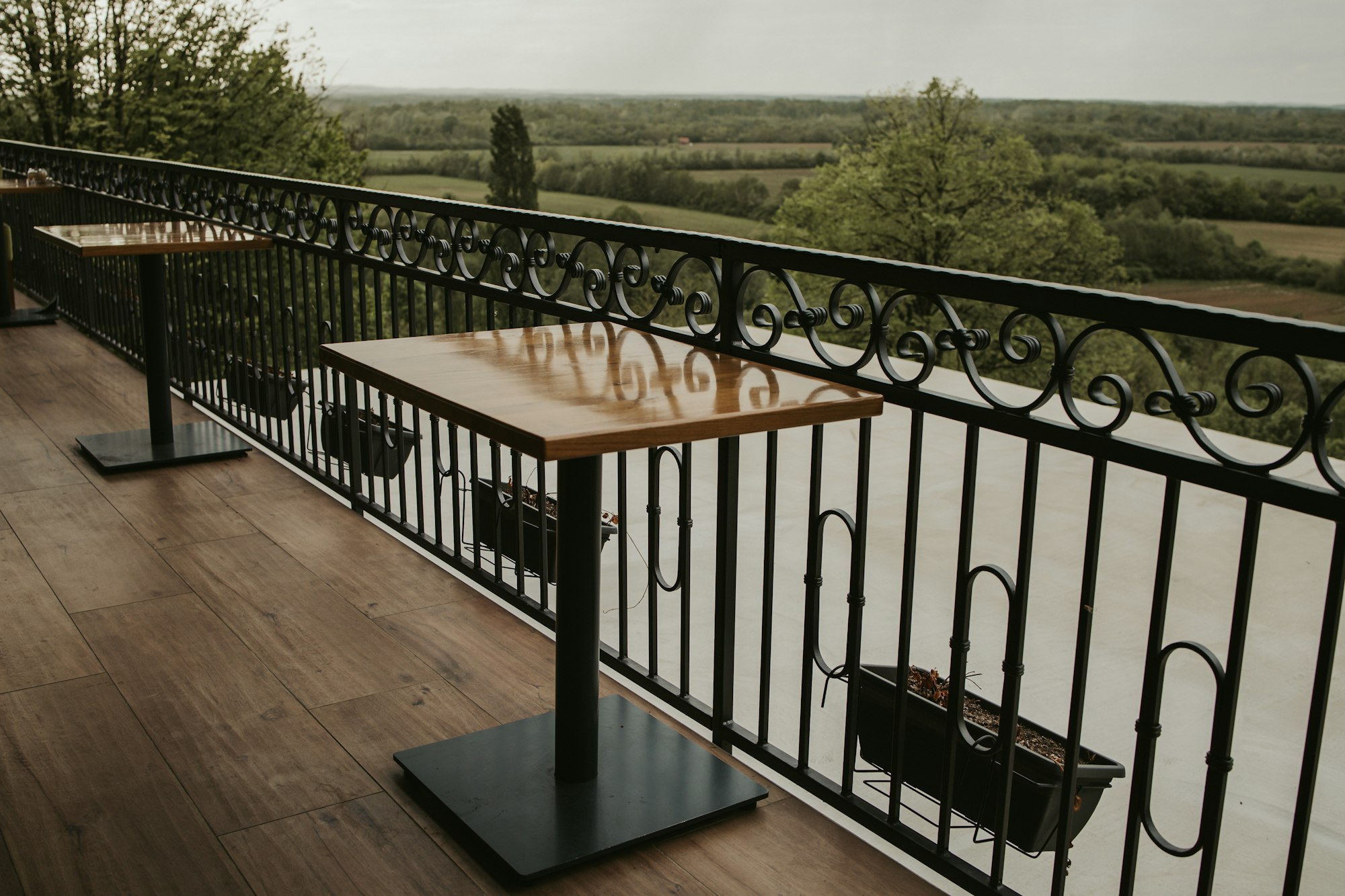Wooden table on the balcony with an iron fence