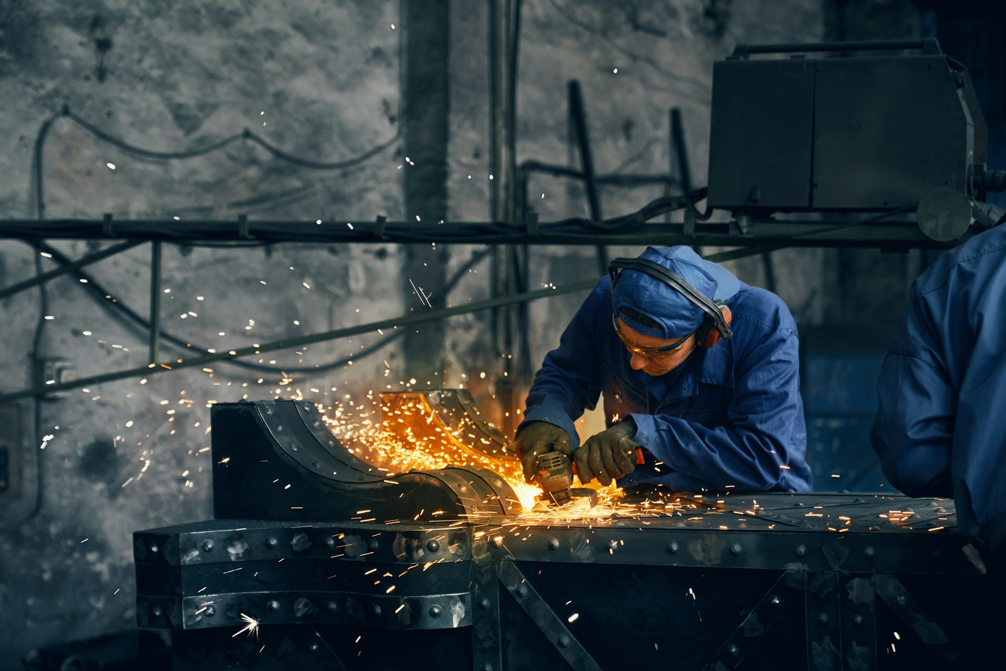 Worker making gates from iron in garage.