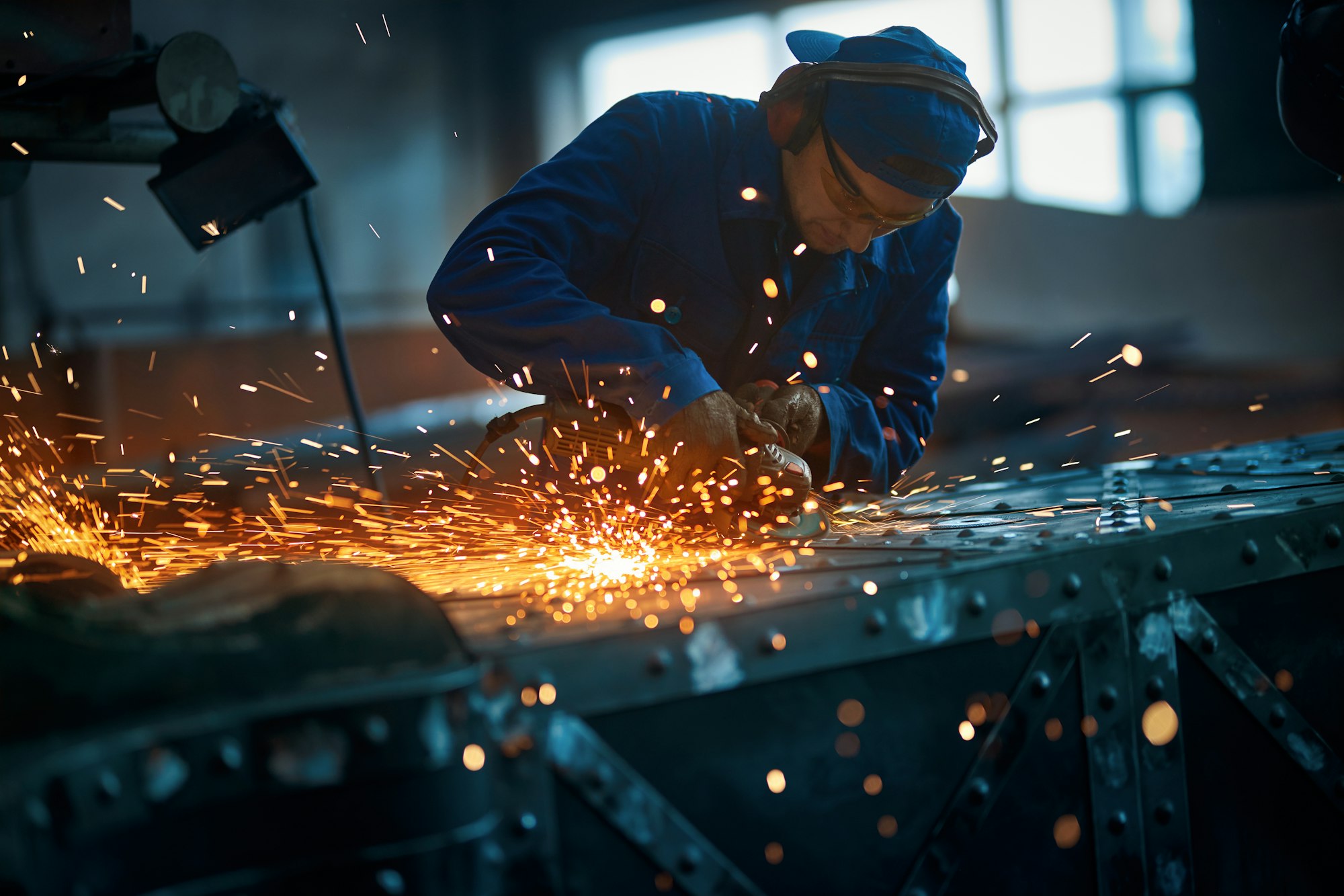 Worker polishing new modern fence with sparks.