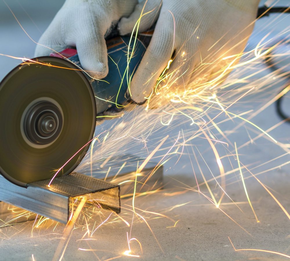 Close-up of worker cutting metal with grinder. Sparks while grinding iron