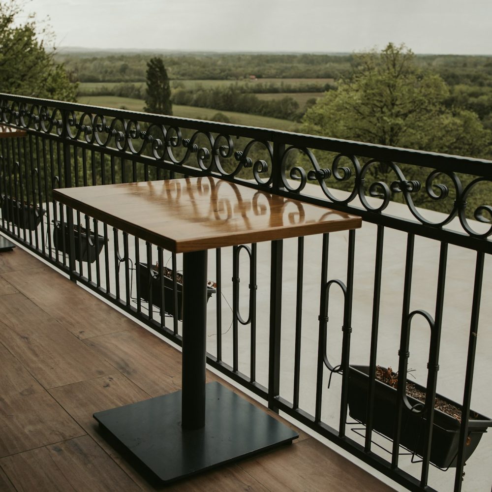 Wooden table on the balcony with an iron fence